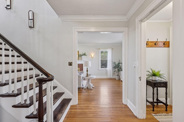 foyer entrance featuring wood finished floors, ornamental molding, stairway, and baseboards