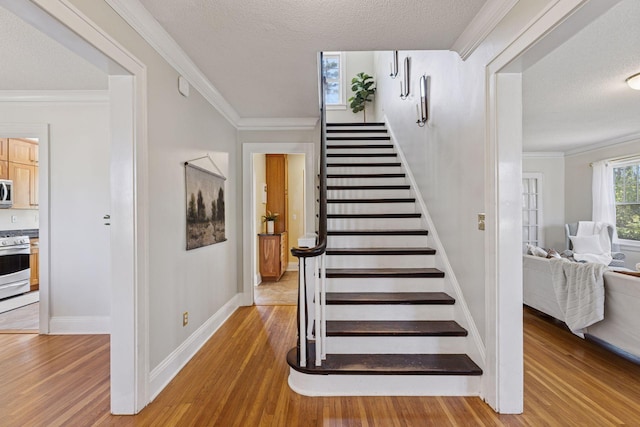 stairs featuring wood finished floors, a textured ceiling, baseboards, and crown molding