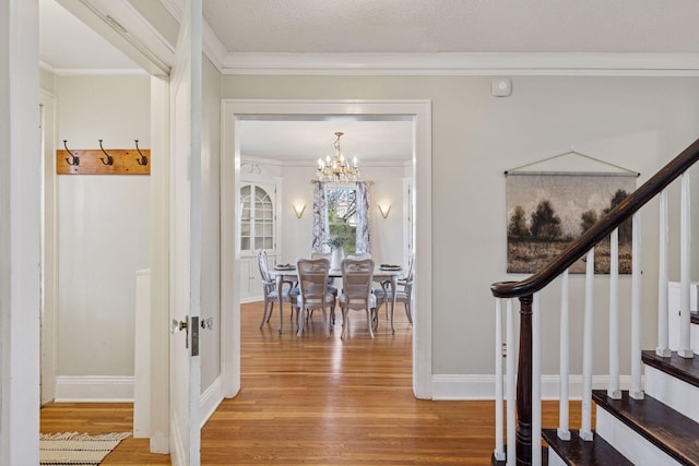 foyer featuring wood finished floors, a chandelier, stairs, ornamental molding, and baseboards