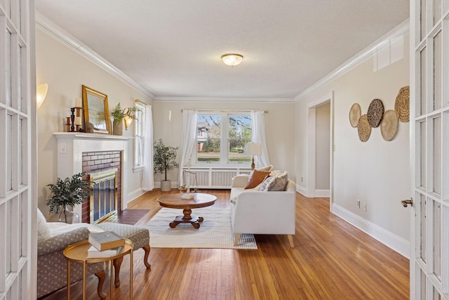 living area with a fireplace, wood finished floors, ornamental molding, baseboards, and radiator