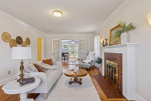 living room featuring wood finished floors, a fireplace, ornamental molding, arched walkways, and a textured ceiling