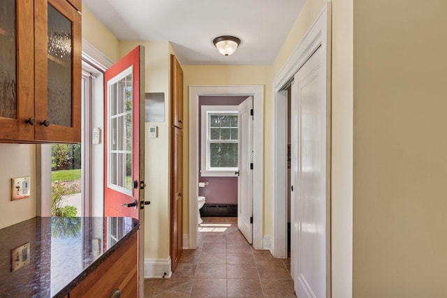 hall with baseboards, tile patterned flooring, and a baseboard radiator
