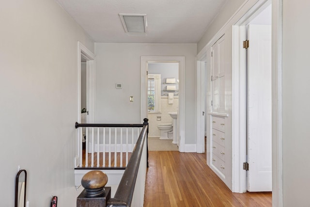 hallway featuring an upstairs landing and light wood-style flooring
