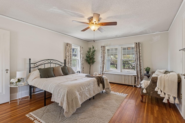 bedroom featuring radiator heating unit, a textured ceiling, hardwood / wood-style floors, ornamental molding, and ceiling fan