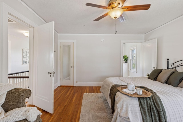 bedroom with wood finished floors, a textured ceiling, ceiling fan, and baseboards