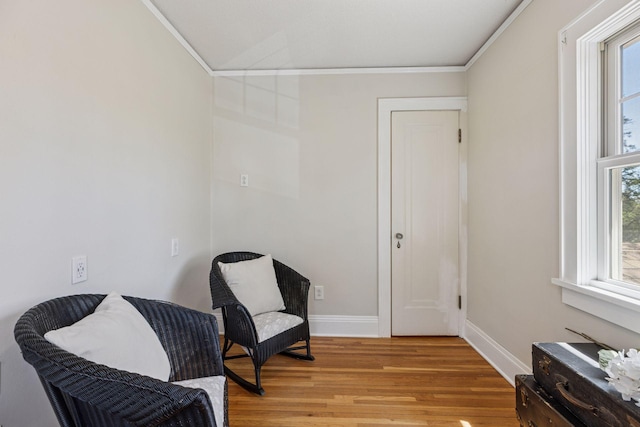 living area with ornamental molding, light wood finished floors, healthy amount of natural light, and baseboards