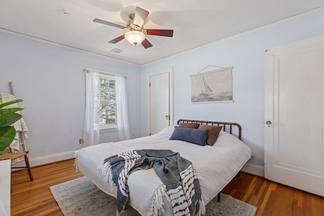 bedroom with wood finished floors, ornamental molding, a ceiling fan, and baseboards