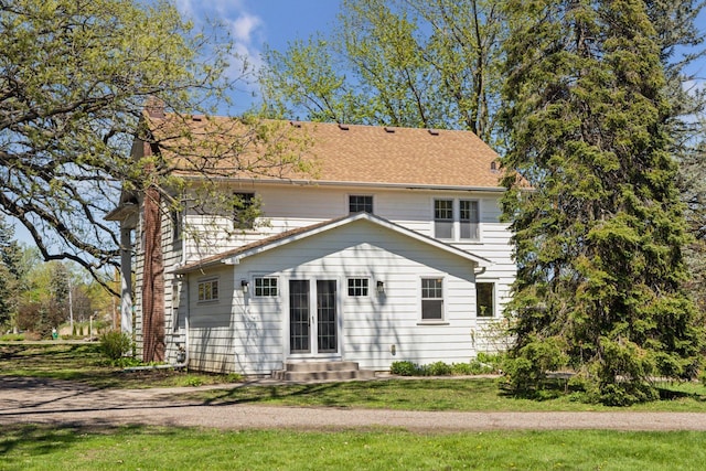 back of house featuring a chimney, entry steps, and a yard