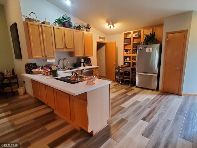 kitchen with appliances with stainless steel finishes, lofted ceiling, light hardwood / wood-style floors, and sink