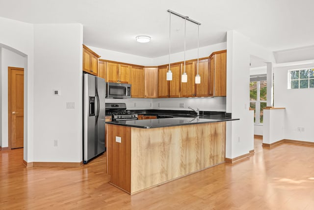 kitchen featuring light hardwood / wood-style floors, stainless steel appliances, kitchen peninsula, and pendant lighting