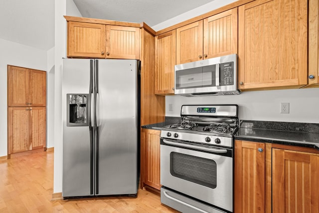 kitchen featuring appliances with stainless steel finishes, a textured ceiling, and light wood-type flooring