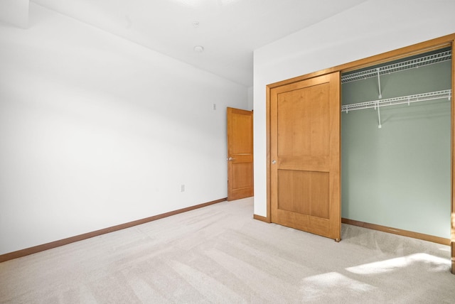 unfurnished bedroom featuring light colored carpet and a closet