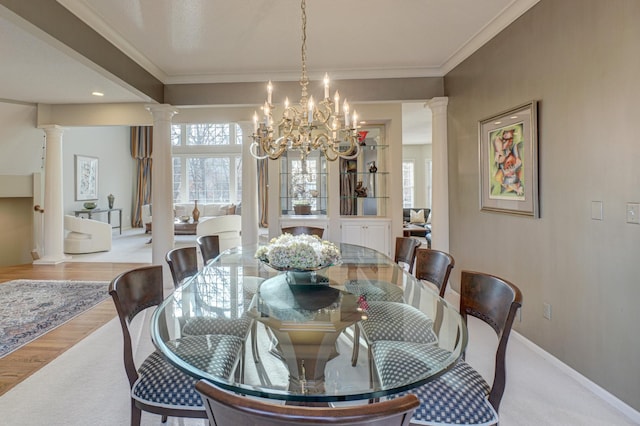 dining space with an inviting chandelier, ornamental molding, light hardwood / wood-style flooring, and ornate columns