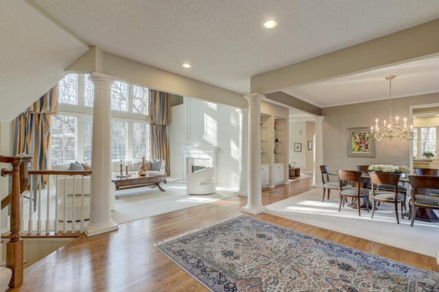 interior space with an inviting chandelier, a textured ceiling, crown molding, and light hardwood / wood-style flooring