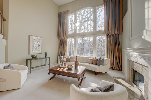 living room with light colored carpet, a towering ceiling, and a fireplace