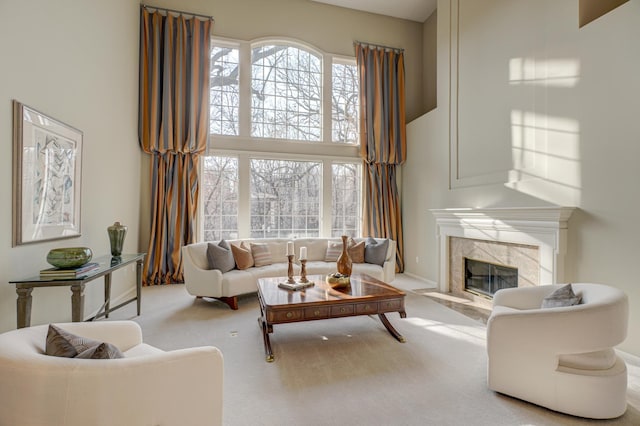 living room featuring a high end fireplace, a high ceiling, and light carpet