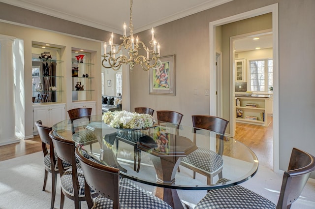 dining space featuring ornamental molding, a notable chandelier, and light hardwood / wood-style floors