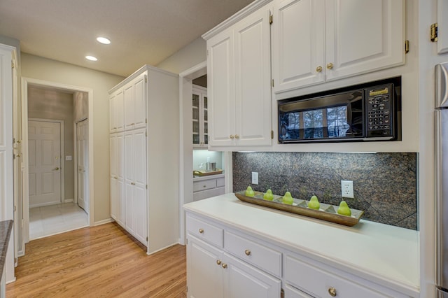 kitchen featuring decorative backsplash, white cabinetry, and light wood-type flooring