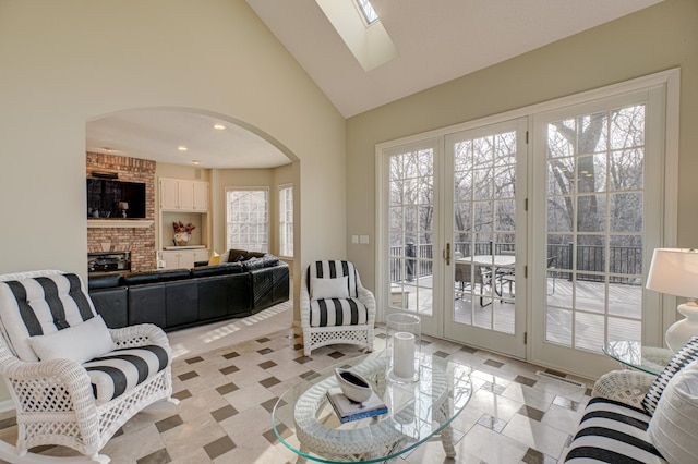 living room with high vaulted ceiling, a skylight, and plenty of natural light