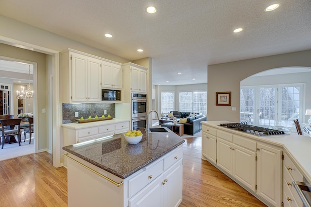 kitchen featuring a center island, white cabinetry, appliances with stainless steel finishes, dark stone countertops, and sink