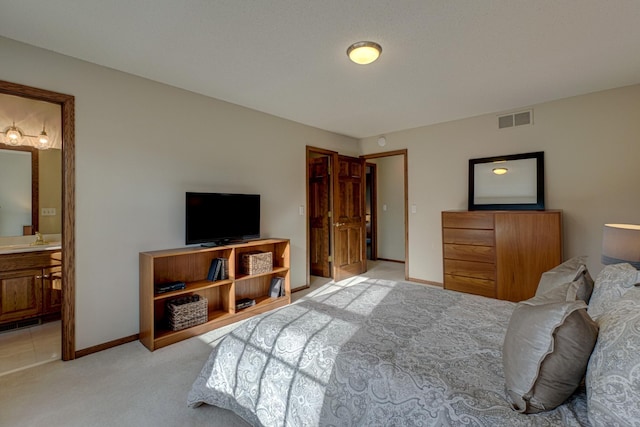 bedroom featuring ensuite bathroom and light colored carpet