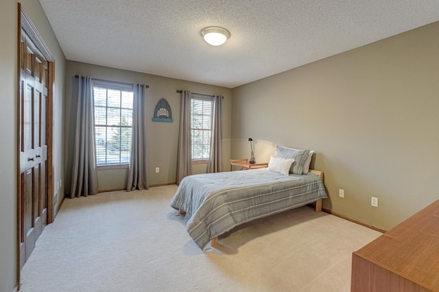 bedroom with a closet, a textured ceiling, and light colored carpet