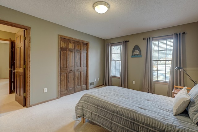 carpeted bedroom featuring a textured ceiling and a closet