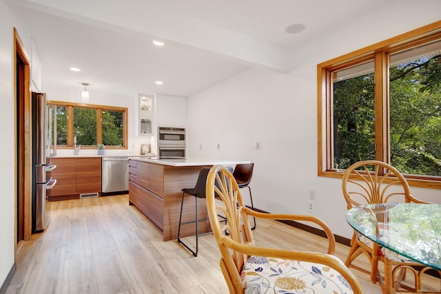 kitchen with light wood-type flooring, white cabinetry, stainless steel appliances, and a wealth of natural light