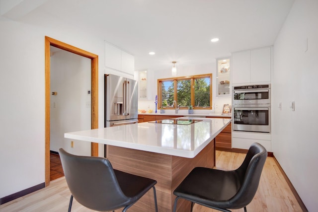 kitchen featuring white cabinets, appliances with stainless steel finishes, light wood-type flooring, and a center island