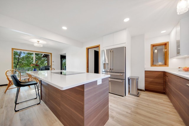 kitchen featuring high end refrigerator, light hardwood / wood-style floors, a center island, and white cabinets