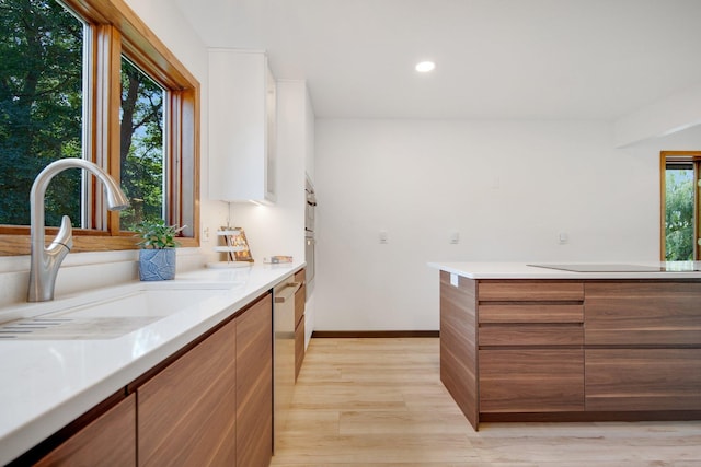 kitchen with black electric stovetop, light hardwood / wood-style floors, sink, and dishwasher