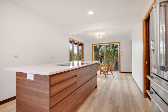 kitchen featuring black electric stovetop, light hardwood / wood-style floors, stainless steel fridge with ice dispenser, and a center island