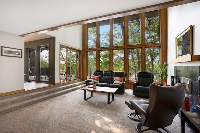 carpeted living room featuring a towering ceiling and a tiled fireplace