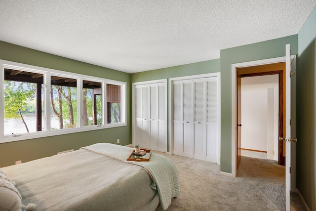 carpeted bedroom featuring multiple closets and a textured ceiling