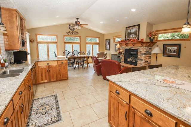 kitchen with plenty of natural light, light stone counters, decorative light fixtures, a fireplace, and sink