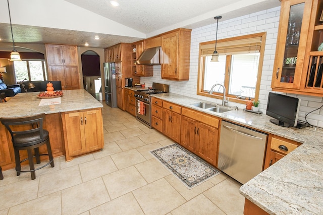 kitchen with sink, stainless steel appliances, wall chimney exhaust hood, and pendant lighting