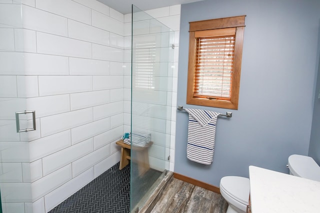 bathroom featuring a tile shower, hardwood / wood-style flooring, and toilet