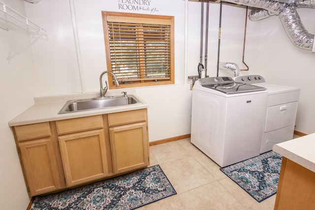 clothes washing area featuring washing machine and clothes dryer, sink, cabinets, and light tile patterned floors