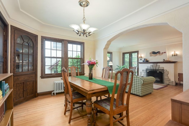 5025 16th Ave S, Minneapolis, MN 55417 - dining room with radiator, arched walkways, a chandelier, light wood-style flooring, and a fireplace with raised hearth
