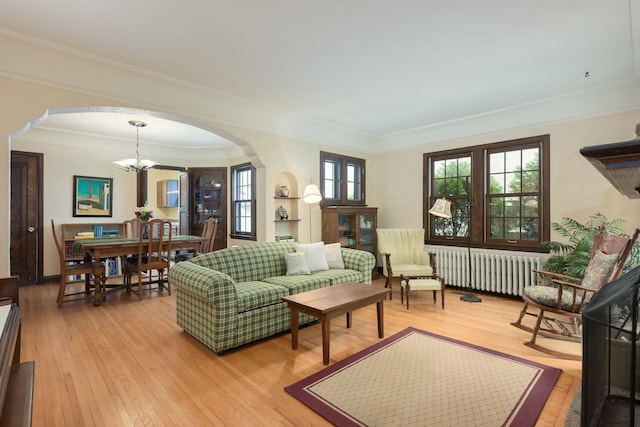 5025 16th Ave S, Minneapolis, MN 55417 - living room with radiator, arched walkways, a chandelier, ornamental molding, and light wood-type flooring