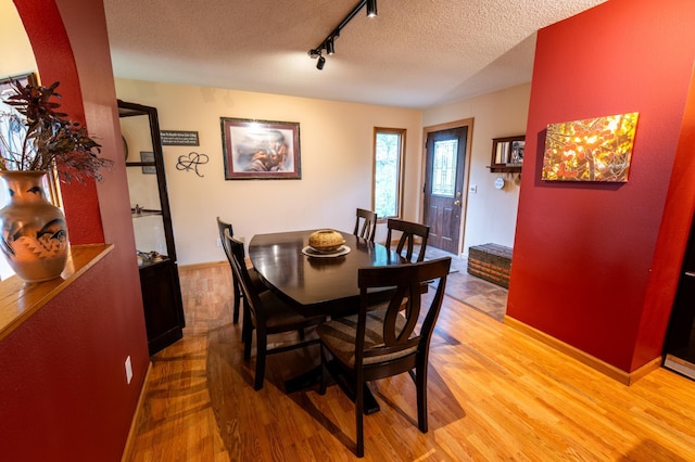 dining room featuring a textured ceiling, light wood-type flooring, and track lighting