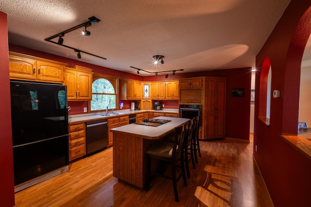 kitchen featuring rail lighting, stainless steel appliances, a kitchen breakfast bar, and a kitchen island