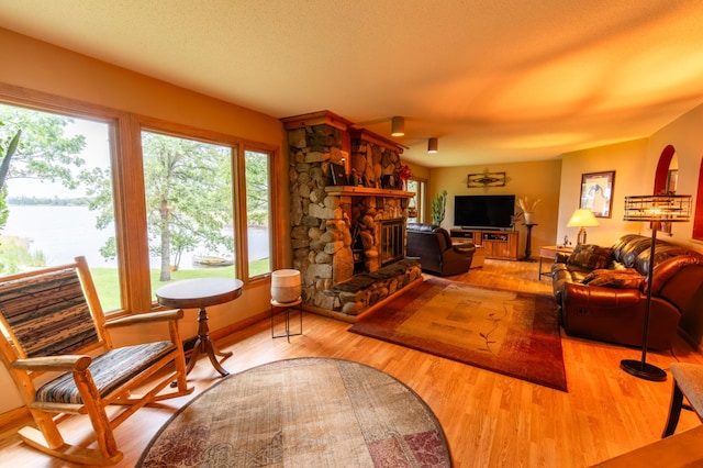 living room featuring light hardwood / wood-style floors, a fireplace, and a textured ceiling