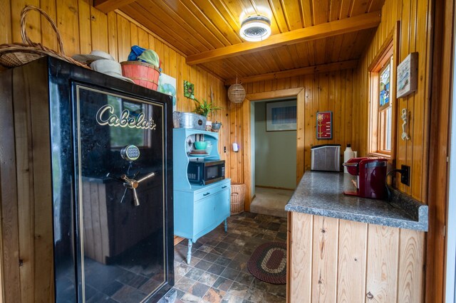 kitchen featuring light brown cabinetry, beamed ceiling, wood walls, and wooden ceiling