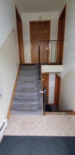 staircase featuring a baseboard heating unit