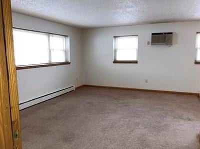 empty room with a healthy amount of sunlight, a baseboard radiator, and carpet