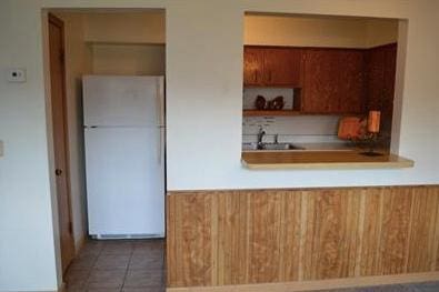 kitchen featuring kitchen peninsula, white fridge, and dark tile patterned flooring