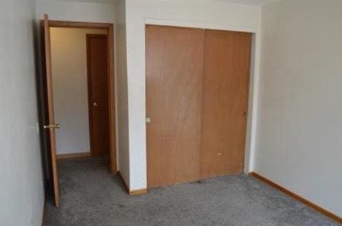 unfurnished bedroom featuring a closet and dark colored carpet