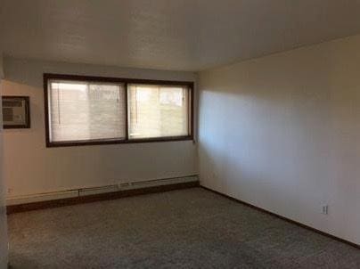 empty room with carpet and baseboard heating