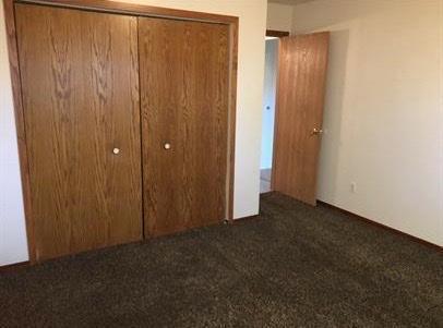 unfurnished bedroom with dark carpet and a closet